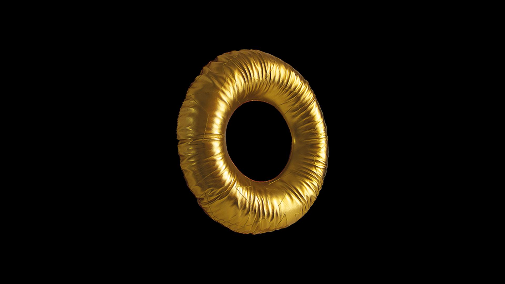 Golden torus sculpture floating against a black background